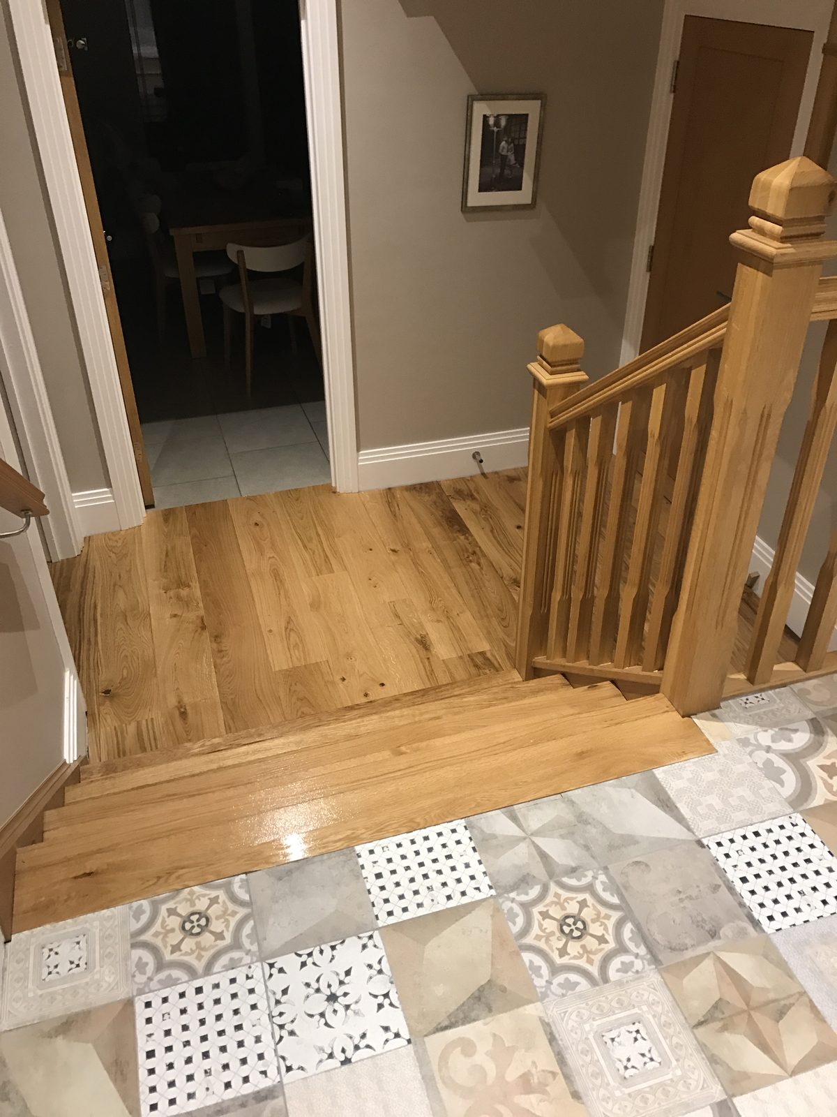 Looking down a short flight of oak steps to the oiled oak hall floor, patterned tiles at the top